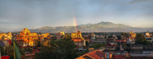 Sunset illuminating distant mountain peaks with warm orange light beneath colorful evening clouds.