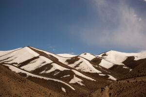 Sand dunes photographed at midday with strong sunlight emphasizing texture and geometric shadows.